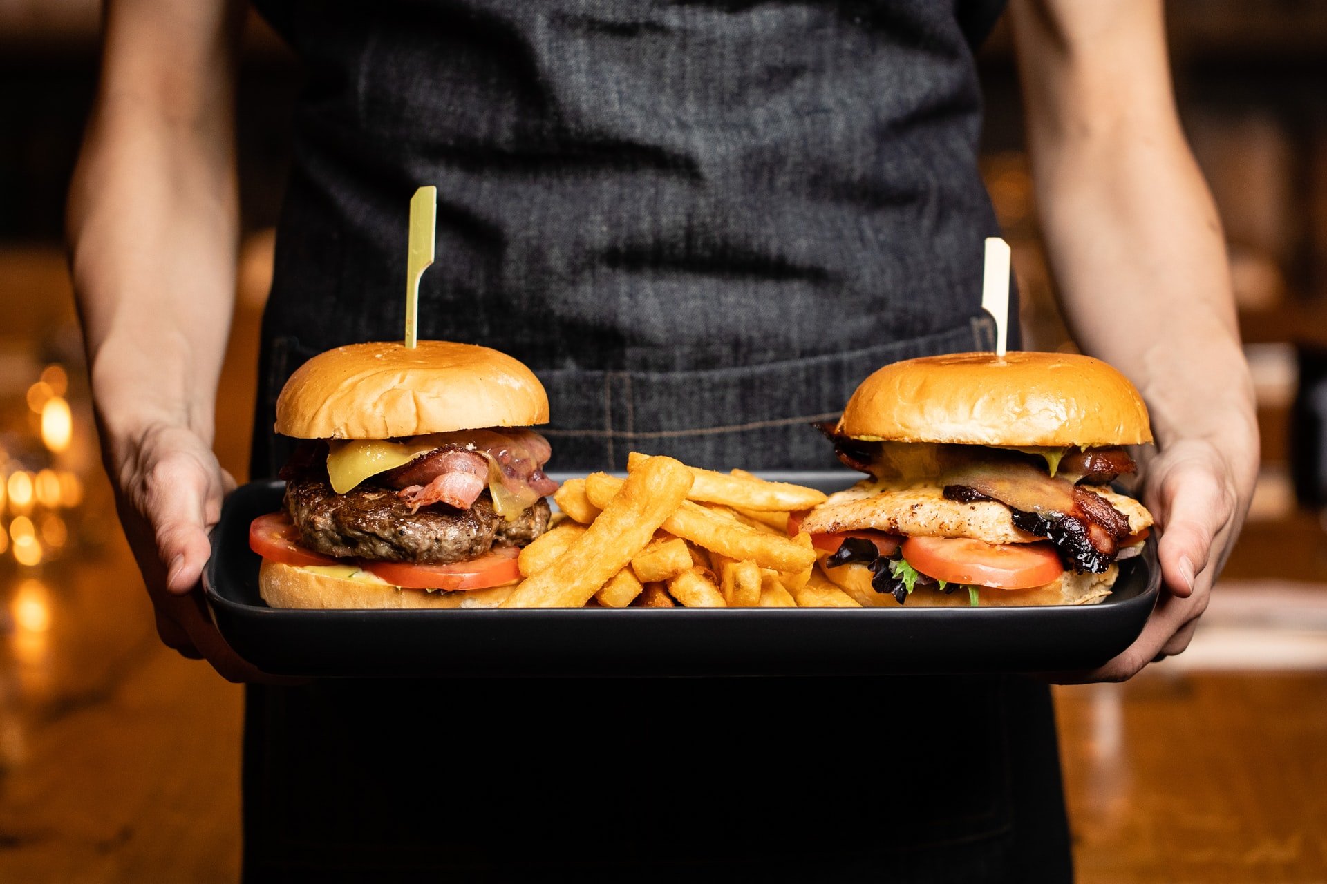 Burgers and fries on a tray being held by a person | Spyglass Realty